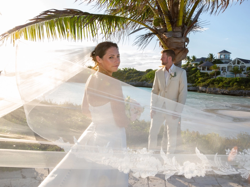 Bride and groom at a coastal destination wedding with palm trees and turquoise water